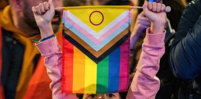 Una menor sostiene una bandera trans (Archivo)