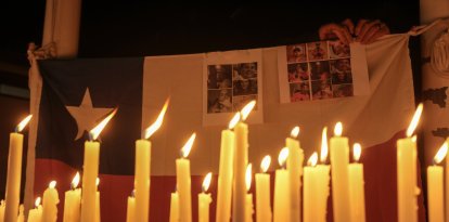 Velas encendidas durante una vigilia con la bandera chilena de fondo y las víctimas de un derrumbe minero, frente a la mina de cobre El Teniente, operada por Codelco, donde un derrumbe mató a un trabajador y atrapó a otros cinco bajo tierra, deteniendo las operaciones en Rancagua, Chile, el sábado 2 de agosto de 2025.