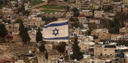An Israeli flag flutters in the wind over the Arab East Jerusalem neighbourhood of Silwan