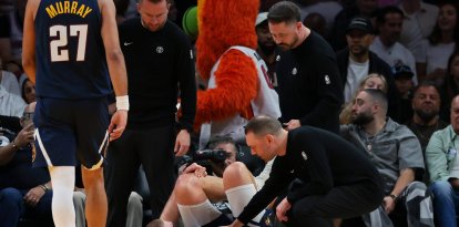 El pívot de los Denver Nuggets, Nikola Jokic (15), se agarra la rodilla izquierda mientras el entrenador David Adelman se acerca a él tras una lesión contra los Miami Heat durante el segundo cuarto en el Kaseya Center.