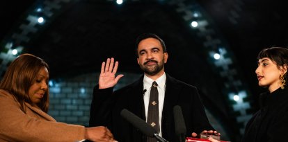 New York mayor-elect Zohran Mamdani (C) places his hand on a Quran