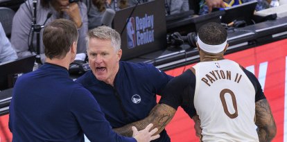 El entrenador jefe de los Golden State Warriors, Steve Kerr, es sujetado por Gary Payton II #0 mientras protesta por una falta no pitada durante el partido de la temporada regular de la NBA 2025 contra los Los Angeles Clippers el lunes 5 de enero de 2026 en el Intuit Dome Arena de Inglewood, California.