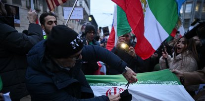 Un manifestante corta la bandera de la República Islámica de Irán