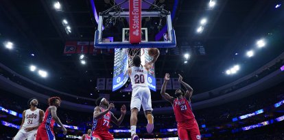 Jaylon Tyson (20), de los Cleveland Cavaliers, realiza un mate entre Joel Embiid (21) y VJ Edgecombe (77), de los Philadelphia 76ers, durante la primera mitad de un partido de baloncesto de la NBA el viernes 16 de enero de 2026 en Filadelfia.