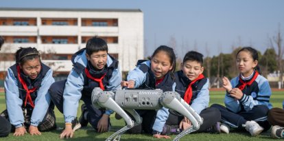 Los alumnos interactúan con un perro robot durante un descanso en clase en la escuela primaria Xinyi.