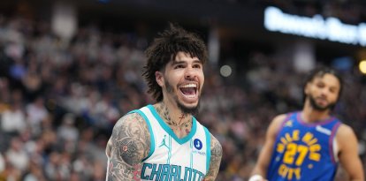 El base de los Charlotte Hornets, LaMelo Ball, reacciona tras clavar el balón para encestar mientras el base de los Denver Nuggets, Jamal Murray, observa en la segunda mitad de un partido de baloncesto de la NBA el domingo 18 de enero de 2026 en Denver.
