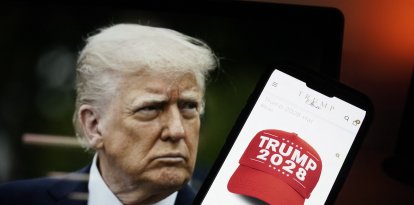 Esta fotoilustración, tomada el 24 de abril de 2025 en Washington, D.C., muestra una imagen del presidente estadounidense Donald Trump junto a un teléfono inteligente con una gorra roja con la leyenda "Trump 2028" en la página web de Trump Store. La tienda en línea de Donald Trump vende ropa con la inscripción "Trump 2028", el año de las próximas elecciones presidenciales estadounidenses