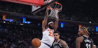 Mitchell Robinson (23), de los New York Knicks, clava el balón frente a Michael Porter Jr. (17) y Noah Clowney (21), de los Brooklyn Nets, durante la primera mitad de un partido de baloncesto de la NBA el miércoles 21 de enero de 2026 en Nueva York.