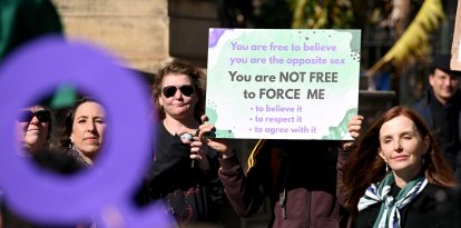 Personas sostienen pancartas y banderas en una manifestación de Women Will Speak en Melbourne el 16 de agosto de 2025, lamentando la erosión de los derechos de las mujeres ante las reivindicaciones de identidad transgénero.