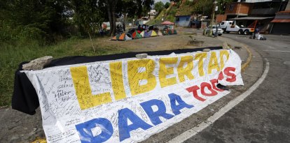 Una pancarta que dice "Libertad para todos" se exhibe frente a la prisión El Rodeo I en Guatire