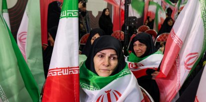 Mujeres con banderas iraníes de luto por las víctimas del terrorismo fallecidas en las protestas en Irán