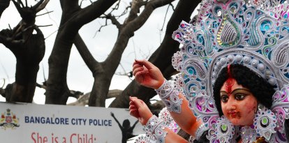 Una procesión pasa junto a una pancarta colocada contra la explotación sexual y la violencia contra las niñas