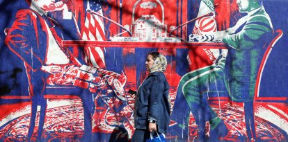 Una mujer iraní pasa junto a un mural que sataniza las conversaciones entre Irán y EEUU