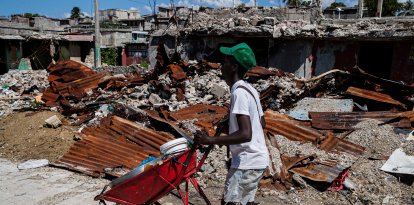 Un comerciante camina alrededor de casas destruidas por bandas armadas en un barrio de Haití