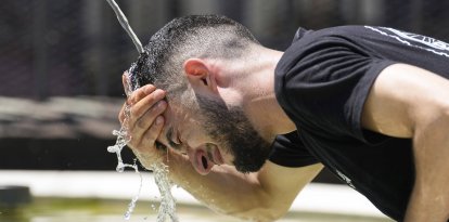 Un joven se refresca en una fuente por las altas temperaturas