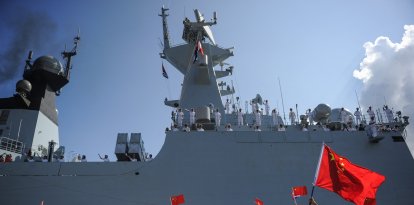 People wave Cuban and PRC flags as several Chinese Navy