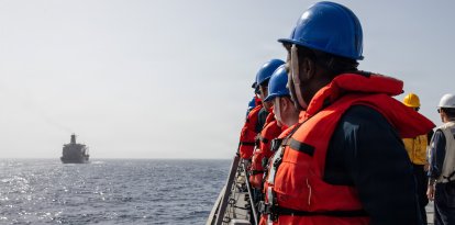 Marineros estadounidenses se apostan en las barandillas del destructor lanzamisiles de la clase Arleigh Burke USS Mitscher (DDG 57) durante una operación de reabastecimiento en el mar con el buque de reabastecimiento de la clase Henry J. Kaiser USNS Henry J. Kaiser (T-AO 187), en el marco de la Operación Epic Fury, el 3 de abril de 2026.