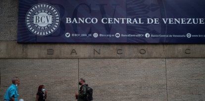 Varias personas caminan frente a la fachada principal del Banco Central de Venezuela en Caracas