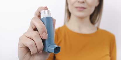 Mujer sosteniendo un inhalador para el asma.