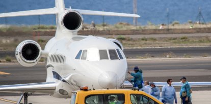 Pasajeros con trajes protectores azules abordan un avión tras ser evacuados del crucero MV Hondius