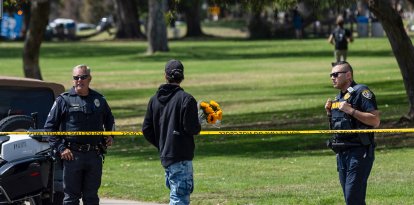 Un hombre lleva flores mientras agentes de la policía de San Diego bloquean el acceso