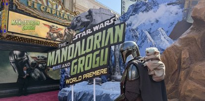Un cosplayer disfrazado de mandaloriano junto a Grogu en el estreno mundial de