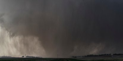 Un violento tornado en forma de cuña, envuelto en lluvia, arrasa tierras de cultivo (Archivo)