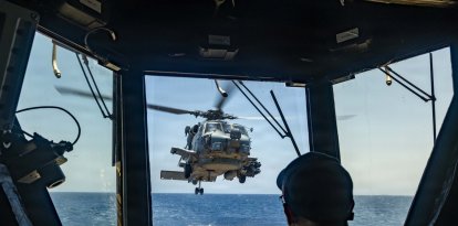 Un marinero estadounidense observa cómo un MH-60R Sea Hawk, adscrito al Escuadrón de Ataque Marítimo en Helicóptero (HSM) 51, despega de la cubierta de vuelo del destructor lanzamisiles de la clase Arleigh Burke USS Rafael Peralta (DDG 115) mientras patrulla el mar Arábigo para hacer cumplir un bloqueo marítimo contra los buques que entran o salen de los puertos y zonas costeras iraníes, el 12 de mayo de 2026. El Rafael Peralta está desplegado en la zona de operaciones de la 5.ª Flota de EE. UU. para apoyar la seguridad y la estabilidad marítimas en Oriente Medio. (Foto de la Armada de EE. UU.)