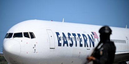 Un avión estadounidense carretea en el aeropuerto Simón Bolívar de Maiquetía. En primer plano, un funcionario de la Policía Nacional Bolivariana.