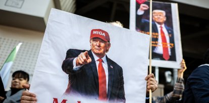Demonstrators hold placards of US President Donald Trump with text that reads "Make Iran Great Again" during a rally supporting political change near the Iranian embassy in Tokyo on March 17, 2026. (Photo by Philip FONG / AFP)