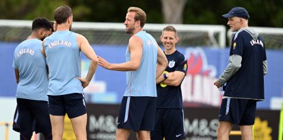 El delantero inglés n.º 9, Harry Kane (C), habla con sus compañeros de equipo mientras el seleccionador alemán de Inglaterra, Thomas Tuchel (D), observa la escena durante una sesión de entrenamiento en el marco de la preparación del equipo para su primer partido del Mundial de fútbol contra Croacia, en la concentración del equipo en Palm Beach Gardens, el 9 de junio de 2026.