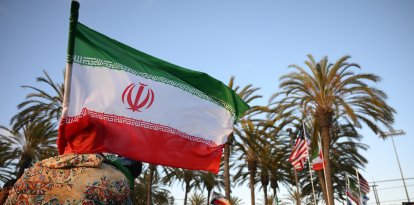 Un hombre sostiene una bandera iraní frente a personas que portan banderas de otros países.