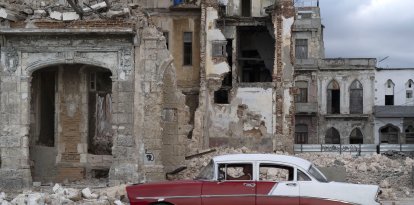 Un coche viejo pasa junto a los escombros de una casa en La Habana (Archivo)