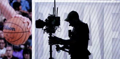 La silueta de un operador de cámara se recorta contra la pantalla del escenario durante la primera ronda de la 78.ª edición del draft anual de la NBA, celebrado en el Barclays Center de Brooklyn el 26 de junio de 2024.