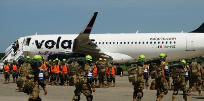 Soldados salvadoreños se preparan para abordar un avión con destino a Venezuela