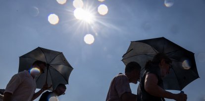 Personas se resguardan del sol bajo en Varsovia.