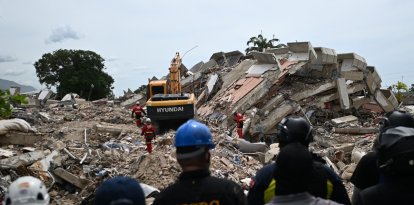 Voluntarios y paramédicos permanecen inmóviles mientras los rescatistas realizan pruebas acústicas en busca de sobrevivientes