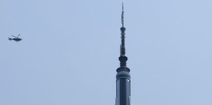 Two helicopters fly near the Empire State Building in New York on July 1, 2026. Two people climbed to the top of the Empire State Building on July 1 and unfurled a banner appearing to read "when the power of love beats the love of power the world knows peace," video published by US media showed. (Photo by TIMOTHY A. CLARY / AFP)