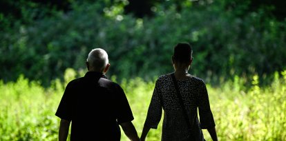 Una pareja de adultos mayores camina por un parque público (Archivo)