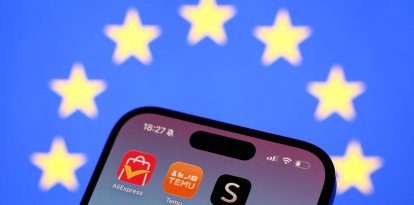 Una bandera de la Unión Europea detrás de las aplicaciones de AliExpress, Temu y Shein