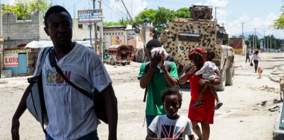 Una familia huye de un barrio tras los disturbios de pandillas ocurridos la noche anterior en Puerto Príncipe, el 20 de abril de 2026.