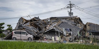 En la imagen se ve una casa derrumbada sobre un coche en Hikawa, en la prefectura de Kumamoto, el 30 de julio de 2026, tras el terremoto que sacudió la zona. El centro comercial Aeon de Kumamoto acababa de reabrir sus puertas en junio, reluciente, más resistente y seguro gracias a las últimas reformas realizadas tras los terremotos de 2016, con la promesa de ser un lugar donde las generaciones pudieran «compartir sonrisas». Sin embargo, a pesar de las exhaustivas obras de refuerzo realizadas en las instalaciones, que sufrieron graves daños hace una década, una explosión provocada por un nuevo terremoto el 28 de julio en la región suroeste de Japón las ha dejado en ruinas.