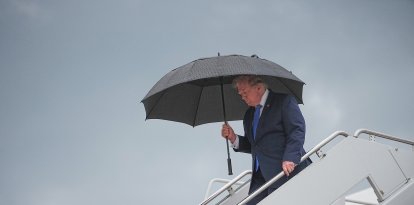 El presidente Donald Trump camina bajo un paraguas al desembarcar del Air Force One en la Base Conjunta Andrews, Maryland, el 2 de agosto de 2026.