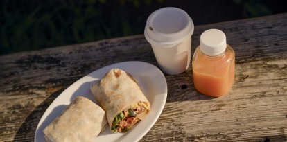 Burritos con café y zumo en una mesa rústica de madera, bajo la cálida luz del sol. California, EEUU