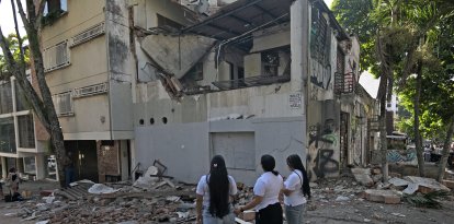 Mujeres miran un edificio caído tras el sismo en Colombia