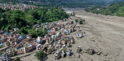 Varias casas parcialmente sumergidas en barro a lo largo de la ribera de un río tras las inundaciones repentinas en Trishuli Bazar, en el distrito de Nuwakot.