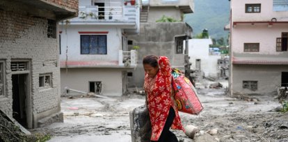 A woman salvages her belongings from her house heavily covered in mud following flash floods at Devighat in Nepals Nuwakot district on August 28, 2026. More than 1,400 people are missing and at least 552 have been killed after a devastating, tsunami-like wall of water gouged a path through the border region between Nepal and Tibet, sweeping away entire villages. (Photo by MANAN VATSYAYANA / AFP)