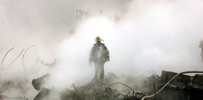 Un bombero camina entre los escombros y los restos humeantes del World Trade Center el 11 de octubre de 2001 en Nueva York. Se celebró una ceremonia interreligiosa en la Zona Cero con motivo del primer mes desde los atentados, que se conmemoró con un breve servicio religioso y un minuto de silencio a las 8:48 de la mañana.