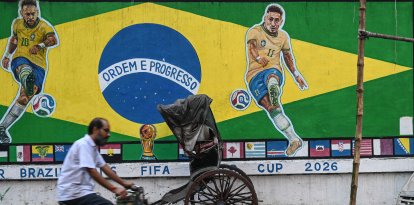 Un ciclista pasa junto a un grafiti con las imágenes del futbolista brasileño Neymar
