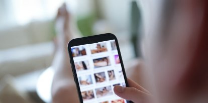 Un joven mira un sitio web pornográfico en un teléfono inteligente (escena escenificada).